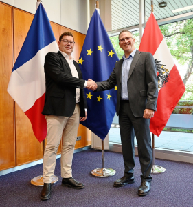 Mit einem Handshake vor den Flaggen von Frankreich, Österreich und der EU besiegelten HarfangLab-CEO Grégoire Germain und IKARUS-COO Christian Fritz die neue Partnerschaft.